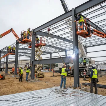 Metal building installation crew setting steel frame