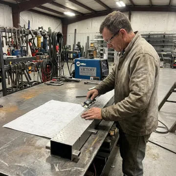 Fabricator measuring stainless steel part during custom metal fabrication