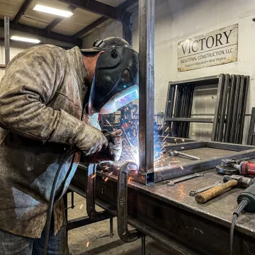 Welder fabricating metal components in an industrial shop