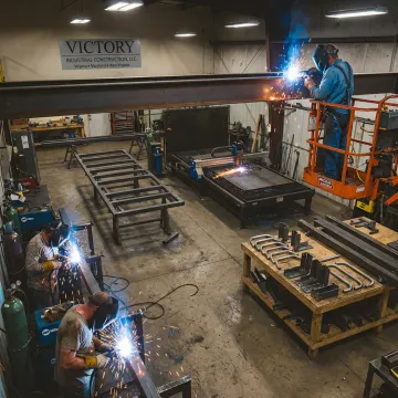 Custom metal fabrication shop with welders and steel parts