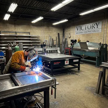 Stainless steel fabrication shop with welder and metal frame