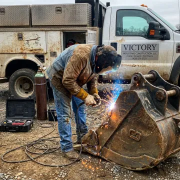 Mobile welder repairing metal equipment on-site