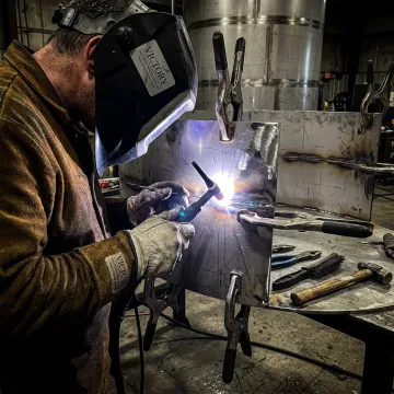 Fabricator welding a stainless steel tank section