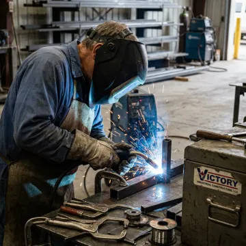 Welder fabricating steel components in a workshop