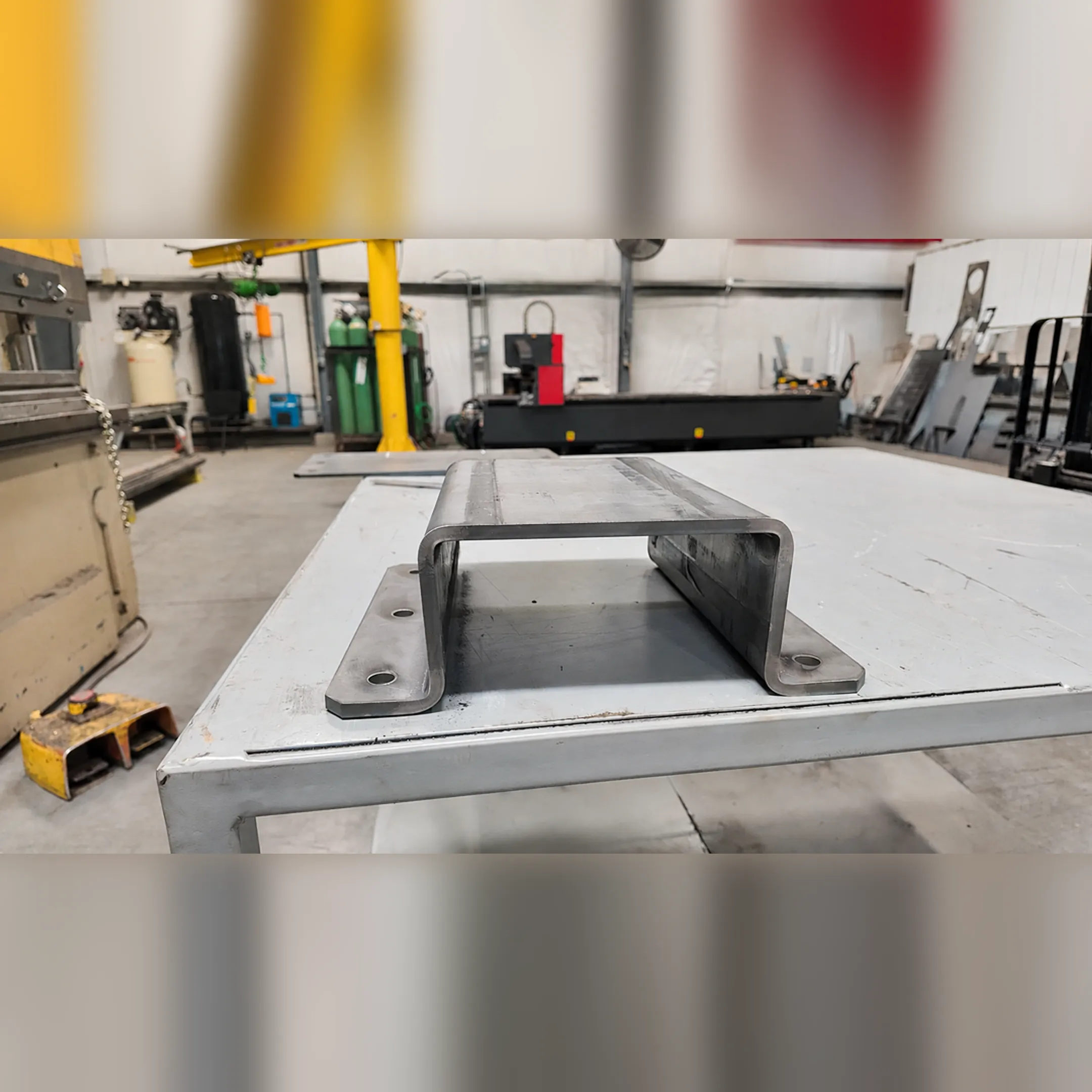 Fabricator measuring custom metal bracket in shop