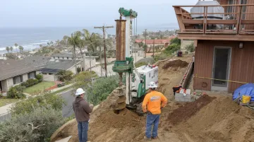 Compact auger drilling equipment installing drilled concrete caisson pier on hillside site