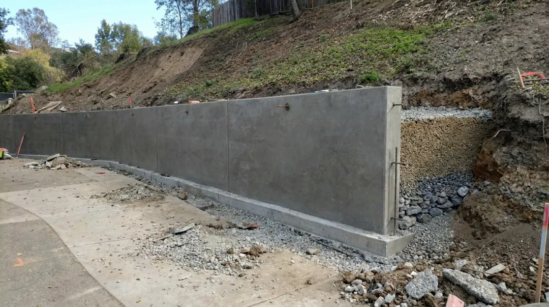Hillside retaining wall construction with concrete block and caisson foundation work