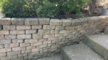 Retaining wall bulging outward showing hydrostatic pressure failure on residential property