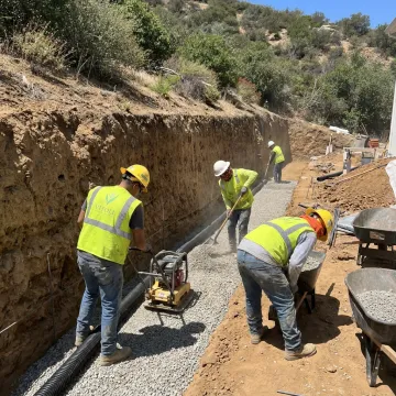 Crew preparing drainage and base for hillside retaining wall