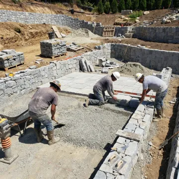 Hardscape crew installing stone patio on hillside property
