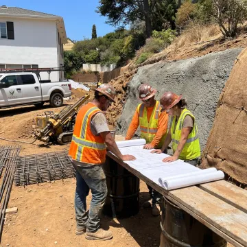 Crew planning caisson drilling on a hillside property