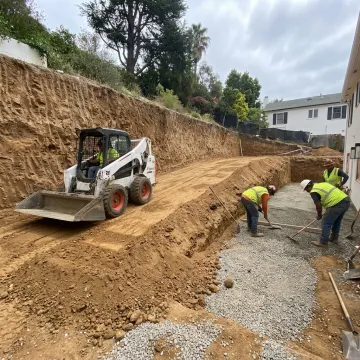 Crew preparing drainage hardscape on a hillside property