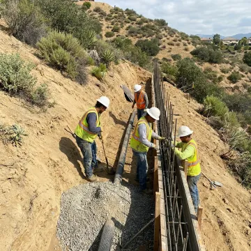 Crew building slope stabilization system on hillside