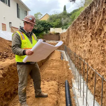 Contractor reviewing retaining wall plans on hillside site