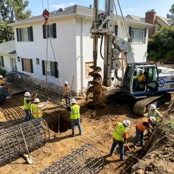 Deep foundation contractors drilling caissons near a home