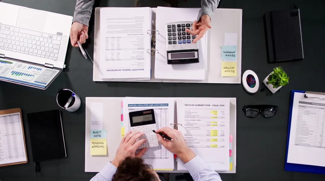 Business professionals reviewing compliance documents and financial reports in office