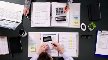 Business professionals reviewing compliance documents and financial reports in office