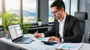 Small business owner reviewing financial records and bookkeeping reports on laptop