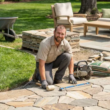 Professional landscape contractor working on custom outdoor living space with hardscape features