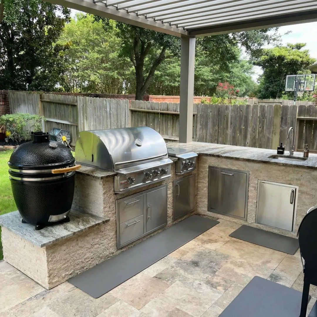 Luxury outdoor kitchen with built-in grill, stone countertops, and covered pergola in Marietta backyard