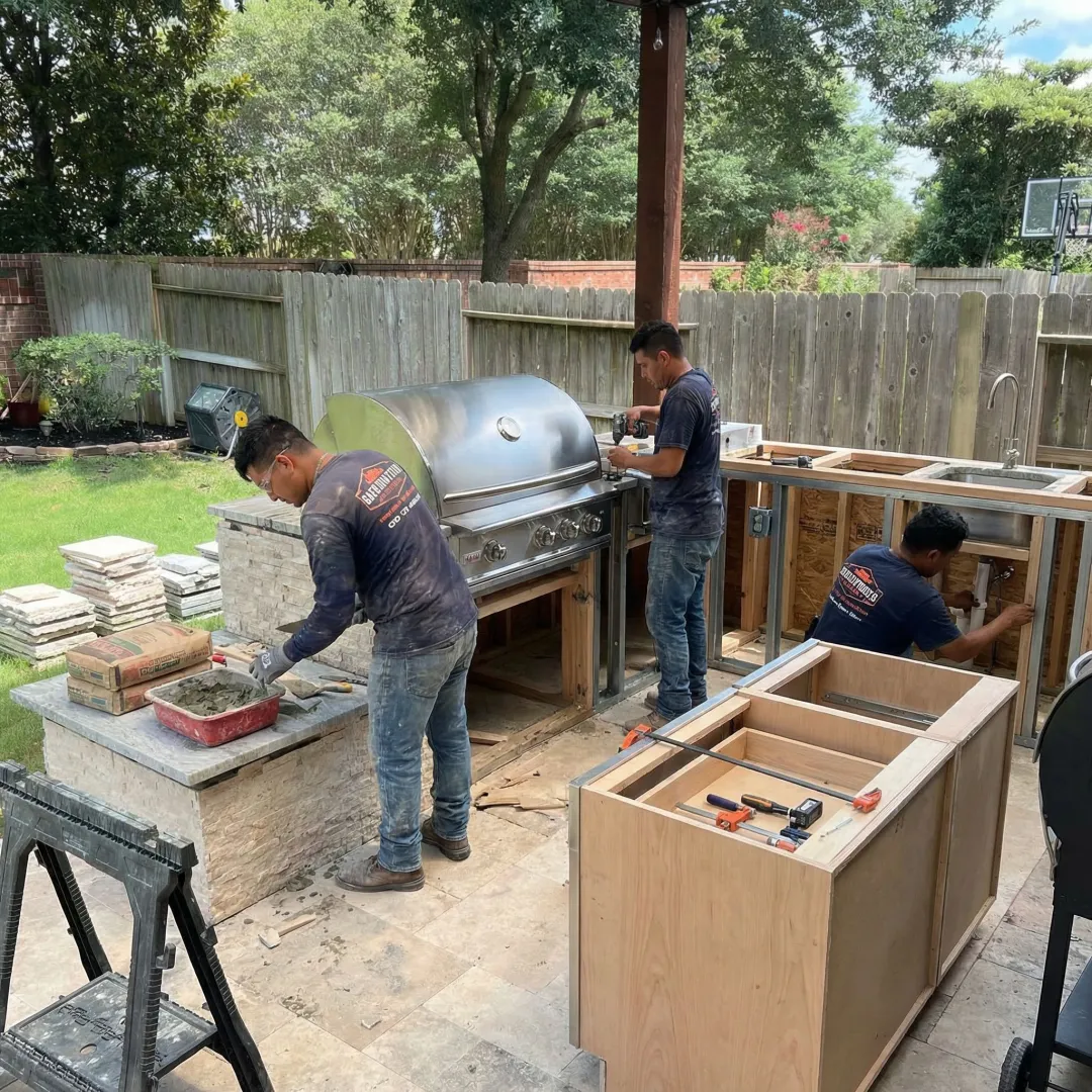 Construction crew installing outdoor kitchen countertops and built-in grill station