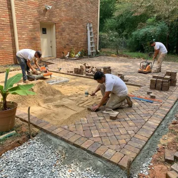 Professional hardscape installation showing cobblestone paver placement and construction process