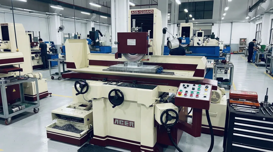 Precision surface grinding machine on production floor showing spindle and magnetic chuck