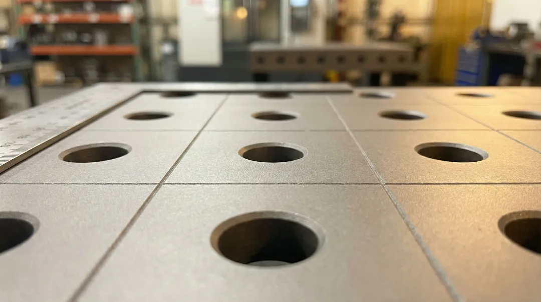 Cast iron welding fixture table surface showing precision-machined hole grid pattern
