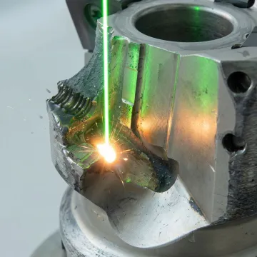 Close-up of precision laser welding repair being performed on industrial cutting tool insert