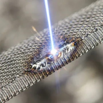Precision laser welding process showing focused beam on miniature metal component