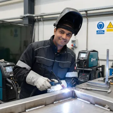 Advanced industrial welding operation showing precision TIG welding on manufacturing components in modern facility