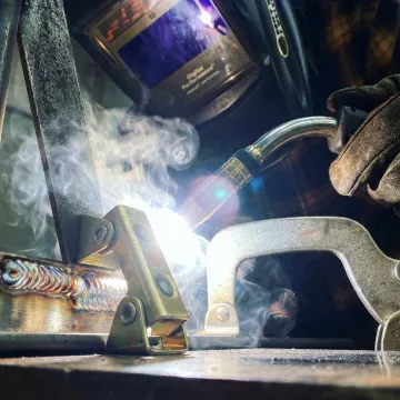 Close-up of MIG welding process showing clean, precise weld beads on steel