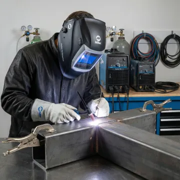 Professional TIG welder working on industrial steel components in fabrication shop