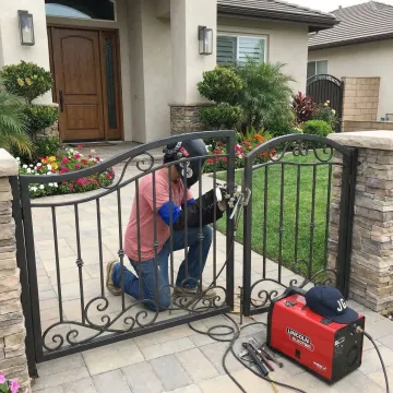 Professional installation of custom wrought iron driveway gate at residential property entrance