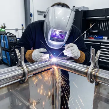 Professional welder performing precision TIG welding on metal structure