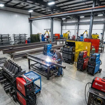 Professional carbon steel fabrication workshop with welding equipment and steel structures