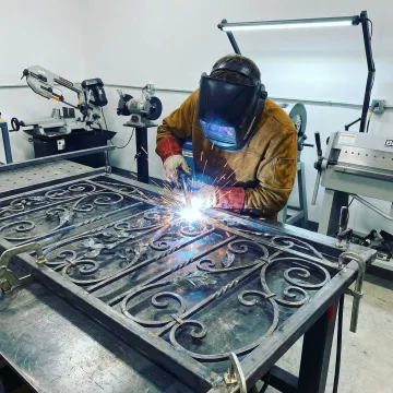 Skilled welder fabricating custom iron railing with precision tools