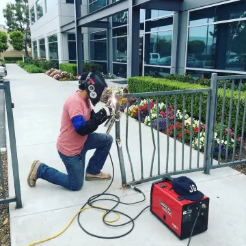 Professional welder repairing damaged commercial fence