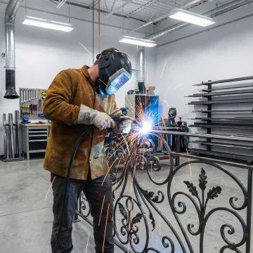 Skilled welder fabricating custom wrought iron railing components
