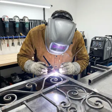 Skilled craftsman working on custom ornamental ironwork in workshop