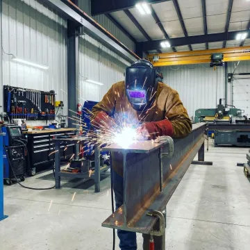 Professional welder working on heavy metal structural steel fabrication