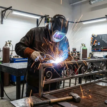 Skilled welder fabricating custom ornate gate in workshop