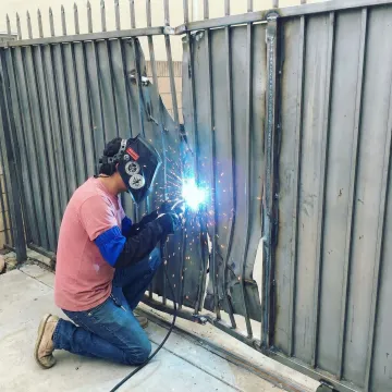 Professional fence repair specialist working on damaged metal fencing