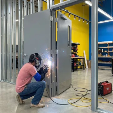 Professional welder repairing a metal door with welding equipment