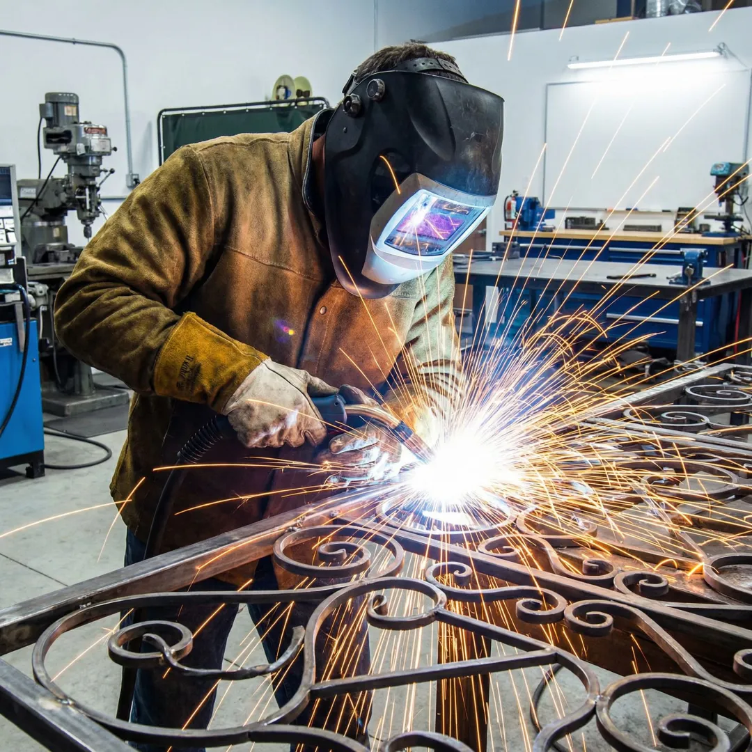 Welder fabricating custom metal gate in workshop