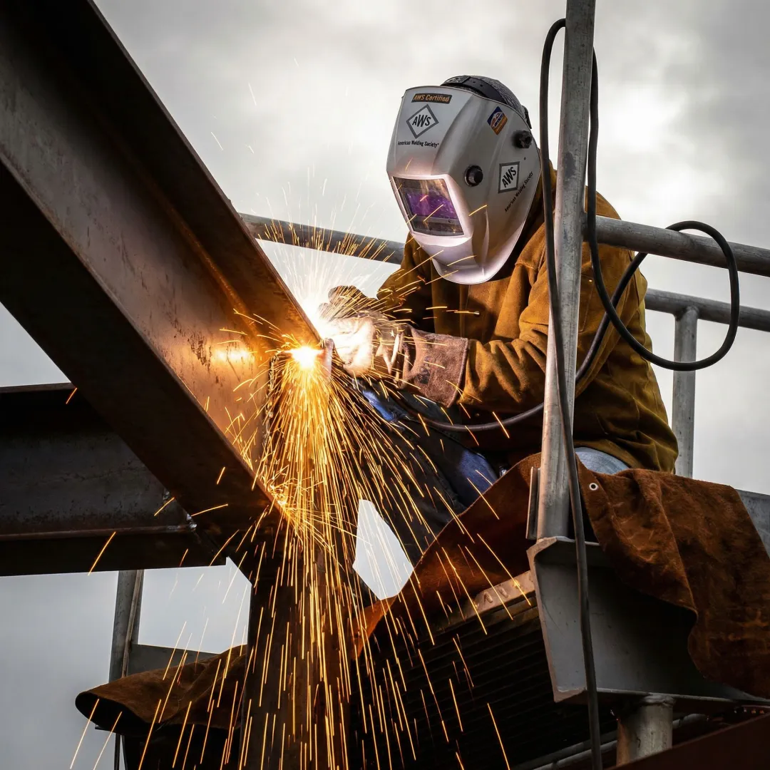 Welder performing structural steel connection on commercial building frame