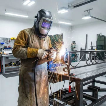 Skilled welder fabricating custom iron staircase railing