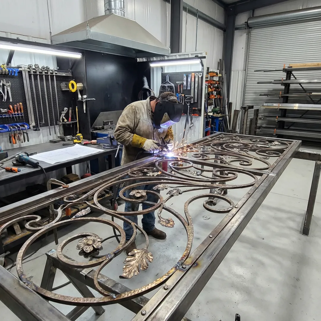 Craftsman welding custom ornamental iron gate in professional workshop