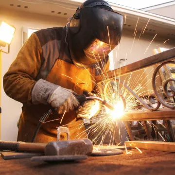 Professional welder fabricating custom metal fence in workshop