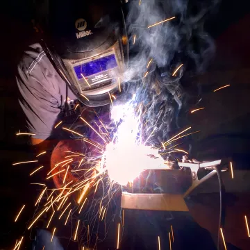 Craftsman welding ornate wrought iron scrollwork in workshop